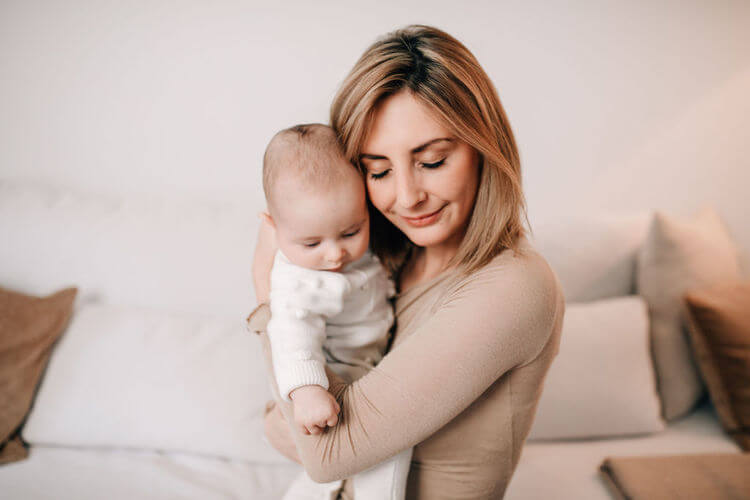 Mama Baby beruhigend im Arm haltend
