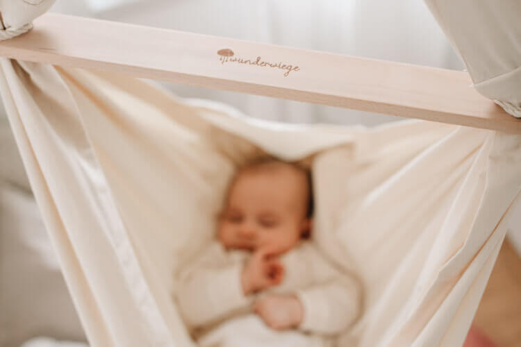 Schlafendes Baby liegend in Babyhängematte WOLLI mit Wunderwiege Logo