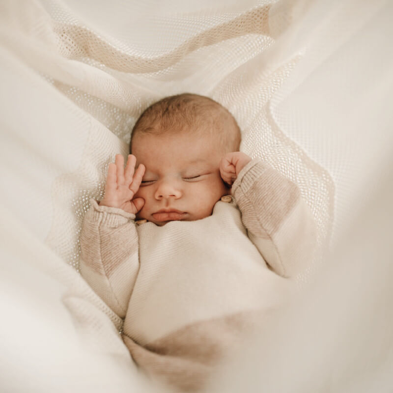 Baby müde in weißer Federwiege MATTI liegend